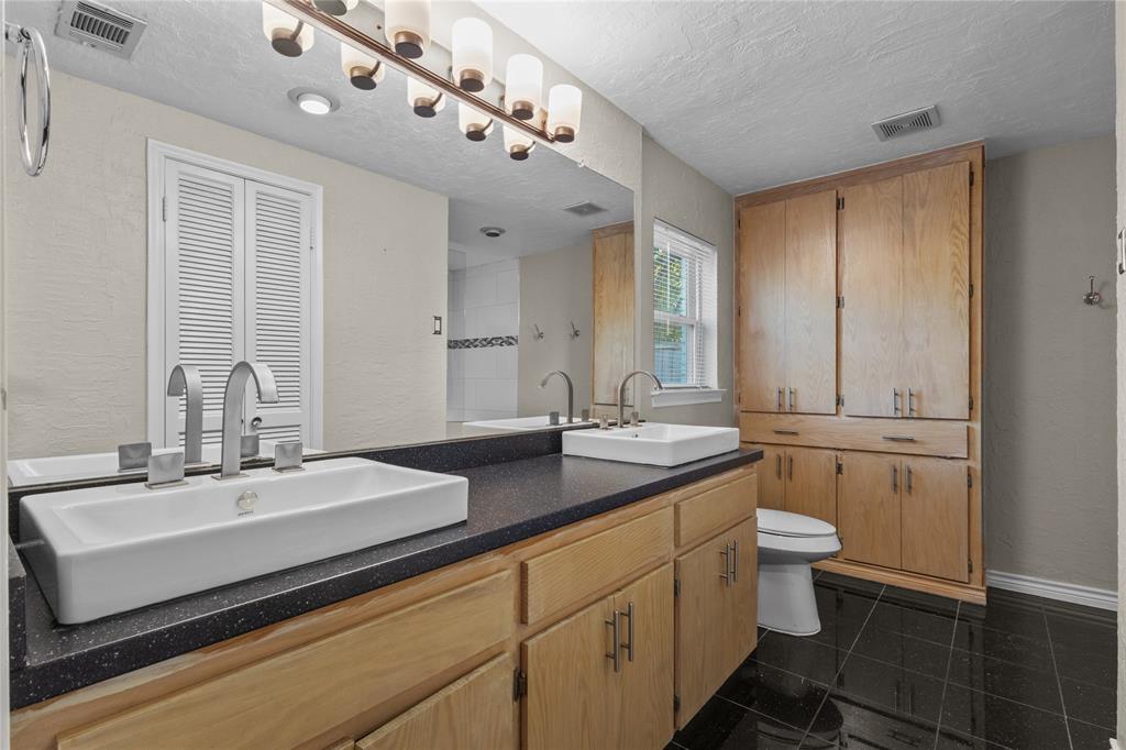 12218 Treeview Lane Farmers Branch, TX 75234 - Photo 11 of 17 a bathroom with a double vanity sink a toilet and a mirror