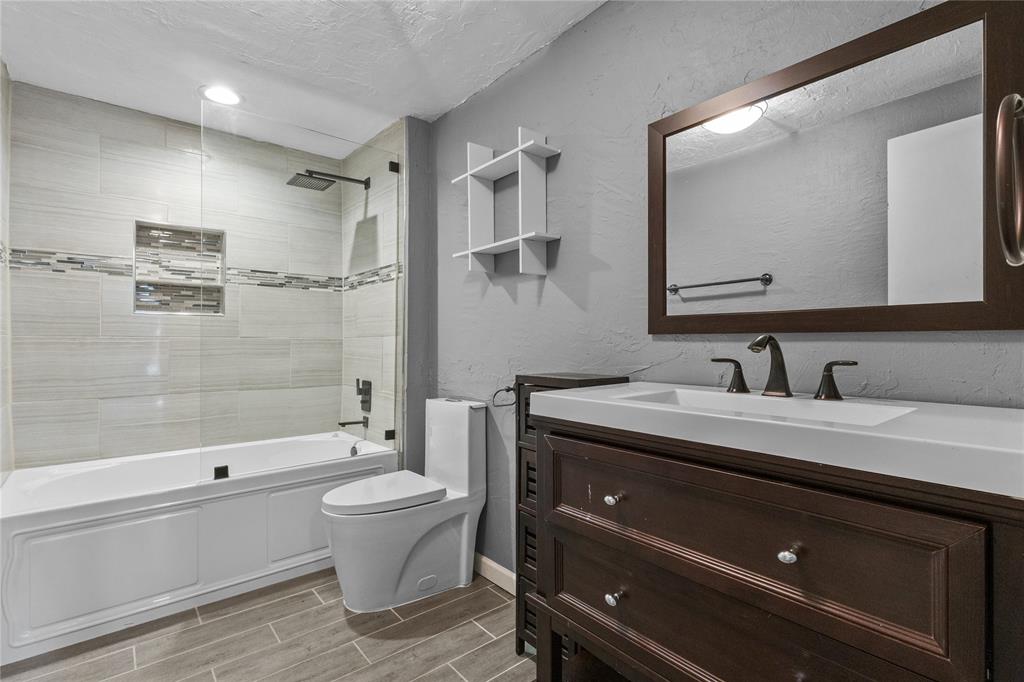 12218 Treeview Lane Farmers Branch, TX 75234 - Photo 13 of 17 a bathroom with a granite countertop sink a toilet and shower