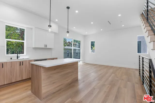 a kitchen with stainless steel appliances granite countertop a refrigerator a sink dishwasher a stove and white countertops with wooden floor