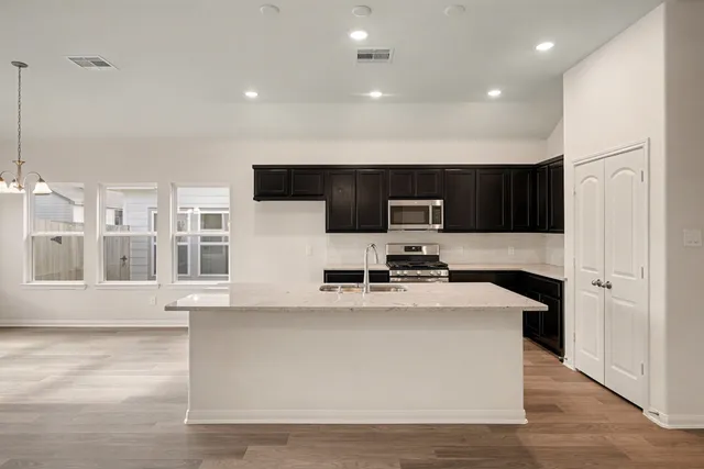 a kitchen with stainless steel appliances a sink a stove a microwave a center island and cabinets