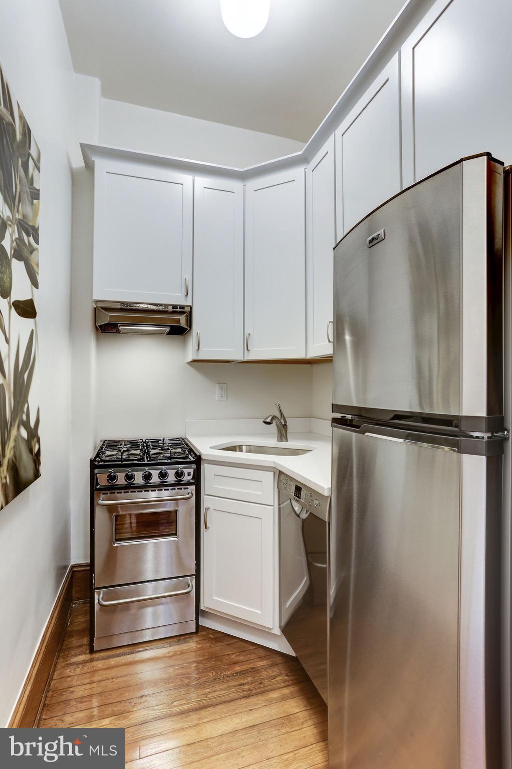 2220 20th Street Northwest, Unit 57 Washington, DC 20009 - Photo 11 of 27 a kitchen with a refrigerator a stove and white cabinets