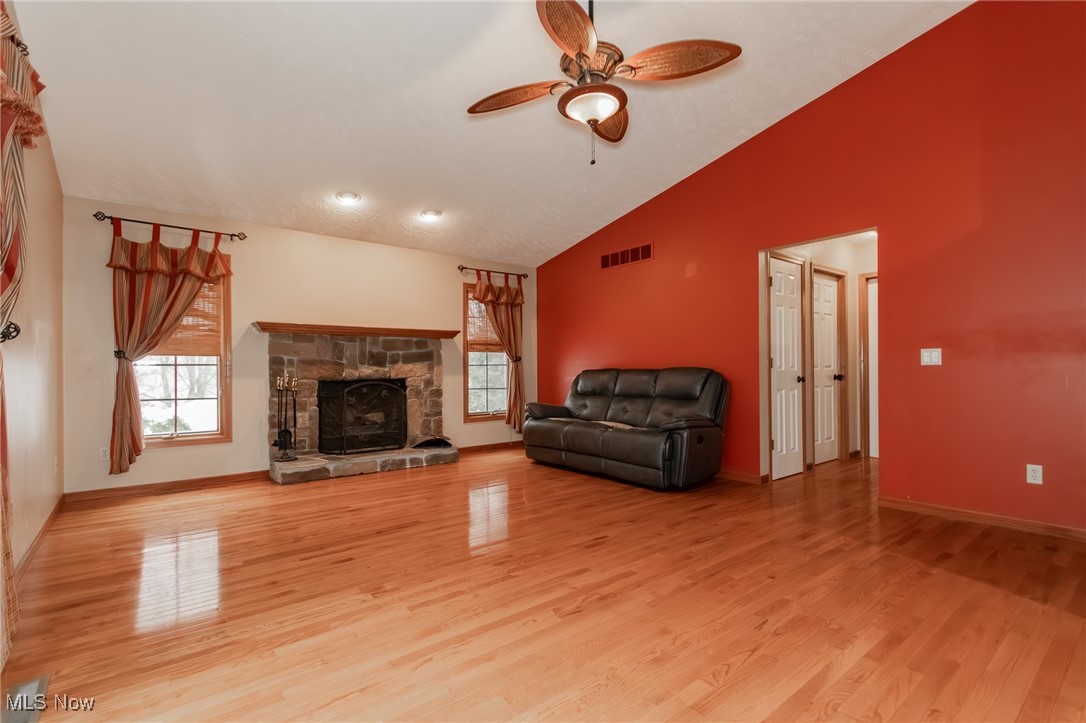 4815 South Ridge Road Perry, OH 44081 - Photo 6 of 48 Unfurnished living room featuring lofted ceiling, a fireplace, light wood-type flooring, and a ceiling fan