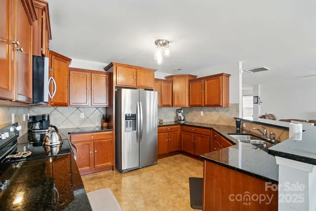 a kitchen with stainless steel appliances granite countertop a refrigerator and a stove