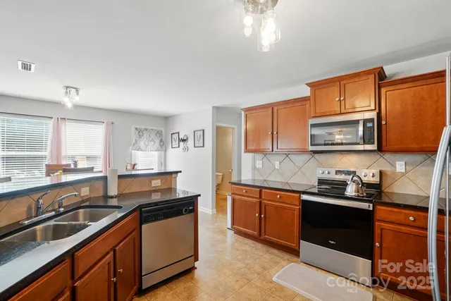 a kitchen with granite countertop stainless steel appliances a sink stove top oven and cabinets