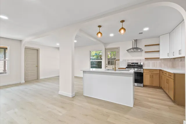 a kitchen with stainless steel appliances granite countertop a stove top oven a sink dishwasher and a refrigerator with wooden floor