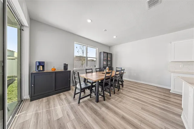 a kitchen with stainless steel appliances a microwave a stove a sink dishwasher a refrigerator and white cabinets with wooden floor