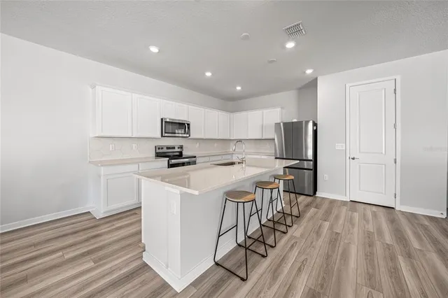 a kitchen with a table chairs wooden floors and appliances