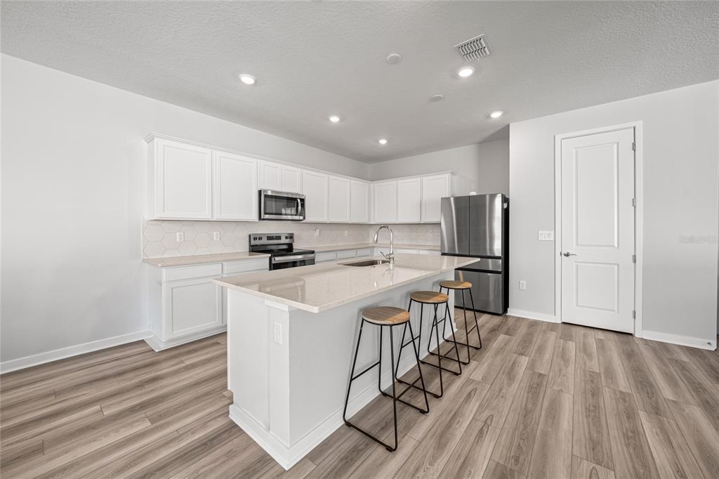 4472 Southwest 84th St Road Ocala, FL 34476 - Photo 21 of 50 a kitchen with stainless steel appliances a microwave a stove a sink dishwasher a refrigerator and white cabinets with wooden floor