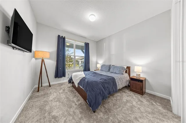 a spacious bedroom with a bed and a flat tv screen on a dresser