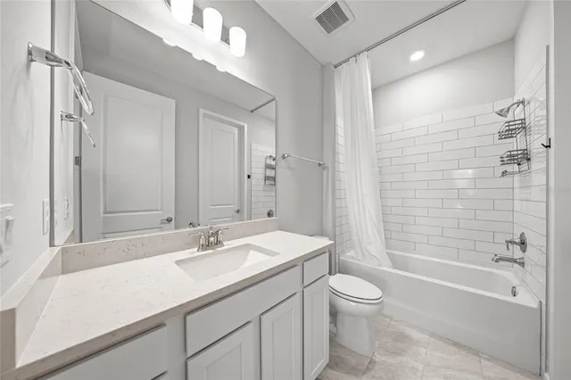 a bathroom with a granite countertop sink a toilet and shower