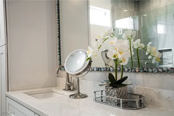 a bathroom with a sink a painting on the wall and a shower