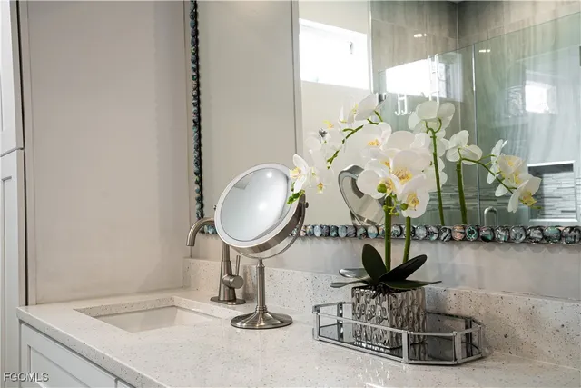 a bathroom with a sink a painting on the wall and a shower