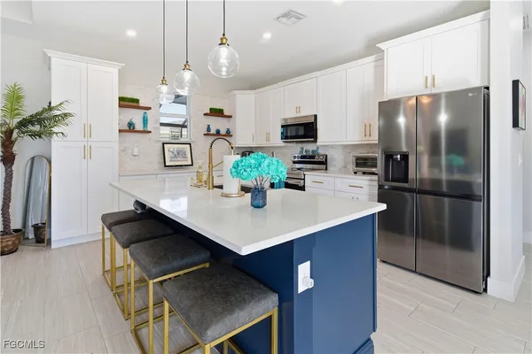 a kitchen with kitchen island a counter appliances a sink and refrigerator