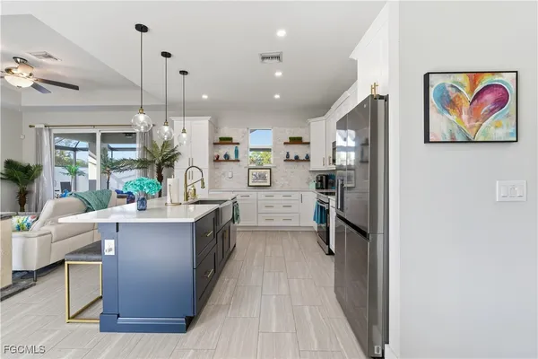 a kitchen with stainless steel appliances granite countertop a refrigerator a sink dishwasher a oven and a dining table with wooden floor