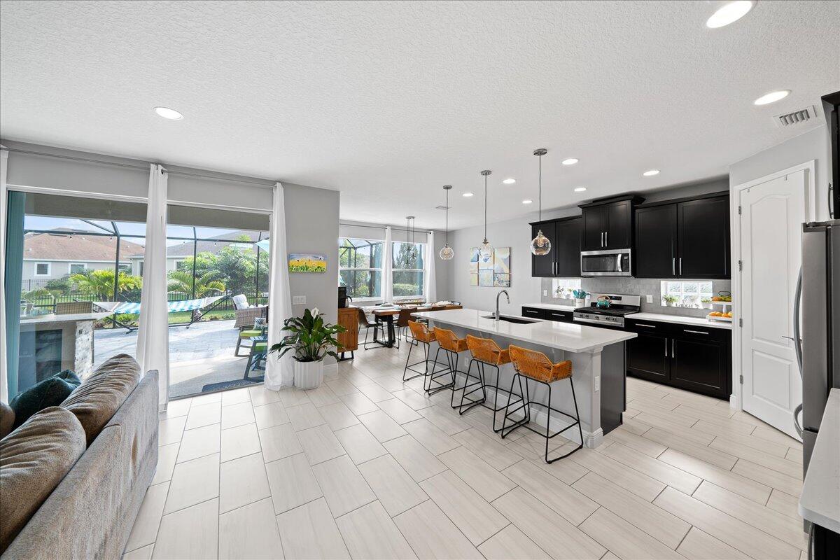 3447 Caviston Way Melbourne, FL 32940 - Photo 5 of 57 a living room with stainless steel appliances kitchen island granite countertop a refrigerator a sink a stove and a oven with wooden floor