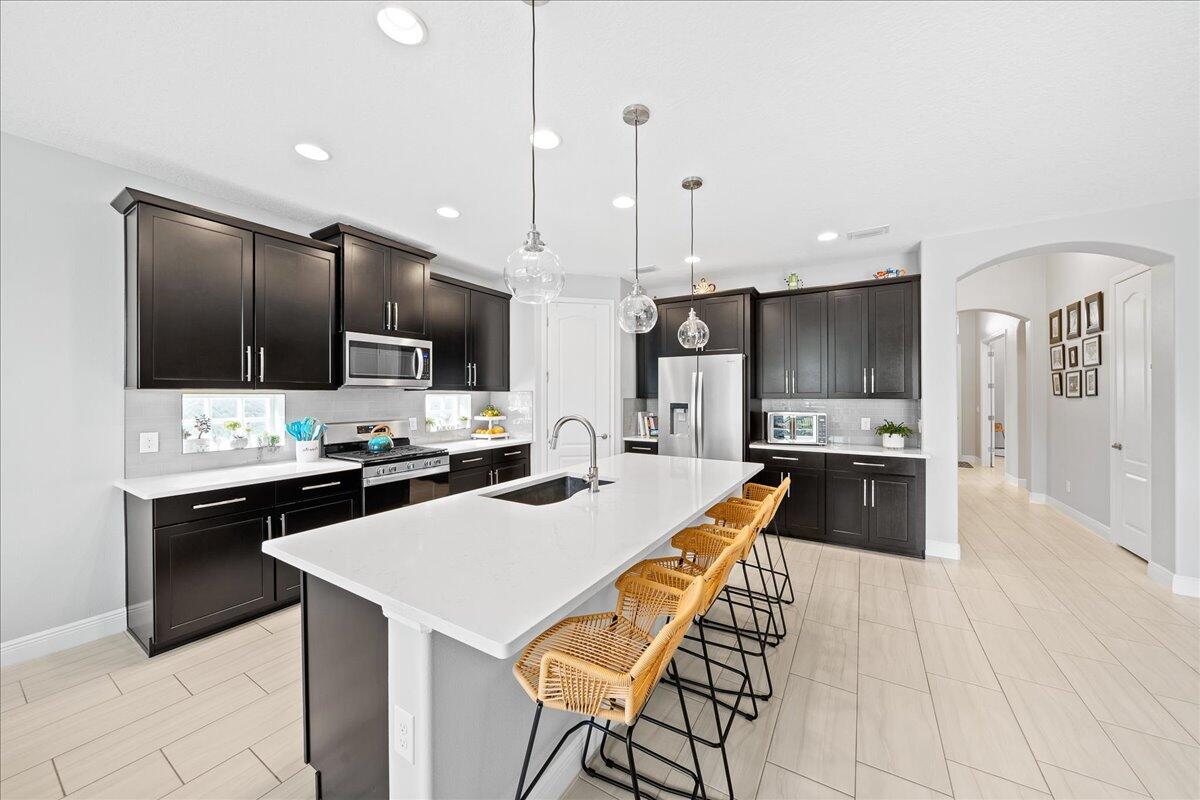 3447 Caviston Way Melbourne, FL 32940 - Photo 6 of 57 a kitchen with stainless steel appliances kitchen island granite countertop a sink a stove a refrigerator and island with wooden floor
