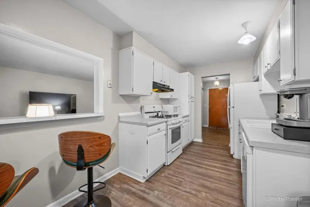 a kitchen with stainless steel appliances granite countertop a stove a sink dishwasher and a refrigerator with wooden floor