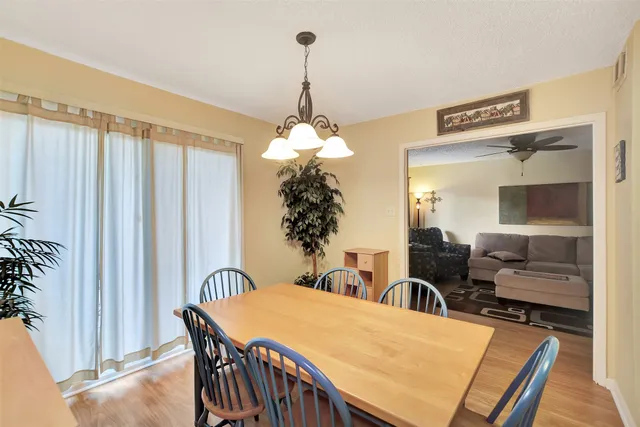 a dining room with wooden floor a chandelier a wooden table and chairs