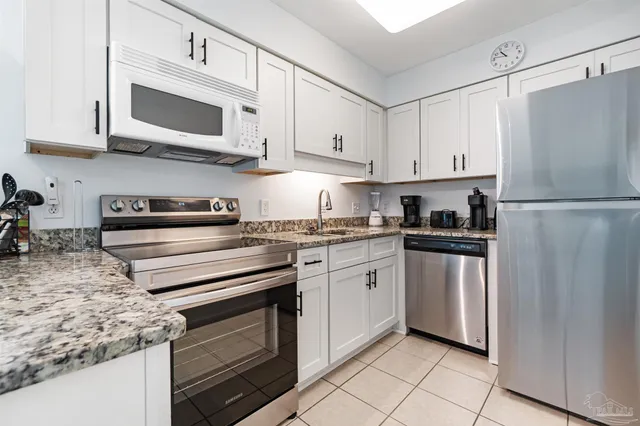 a kitchen with stainless steel appliances granite countertop a refrigerator stove a sink and a microwave