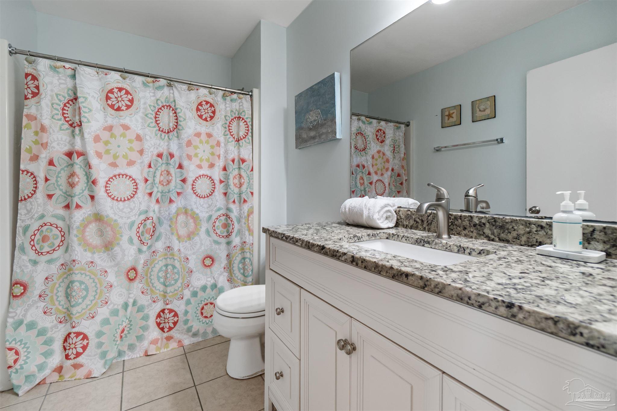 13785 Perdido Key Drive, Unit G3 Perdido Key, FL 32507 - Photo 29 of 30 a bathroom with a granite countertop sink a toilet and a shower curtain