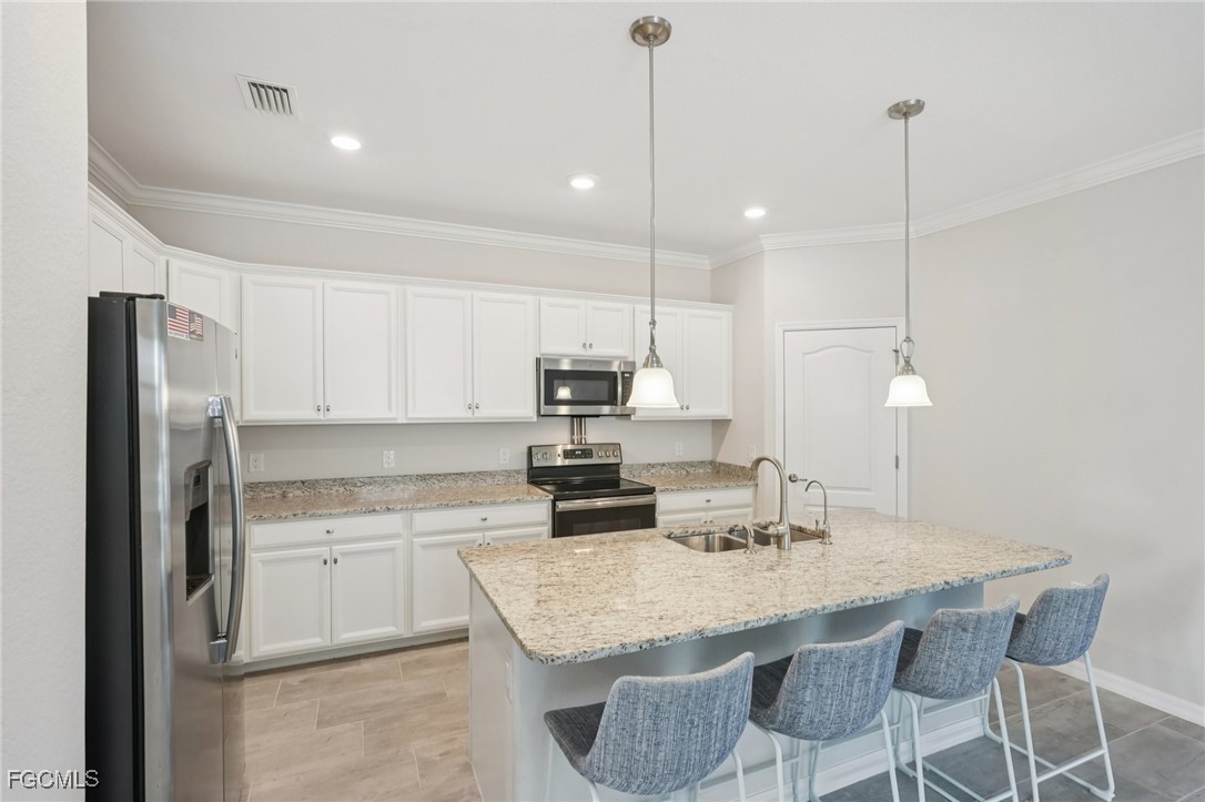 11872 Arbor Trace Drive Fort Myers, FL 33913 - Photo 9 of 50 a kitchen with stainless steel appliances granite countertop a sink a stove a refrigerator and island with wooden floor