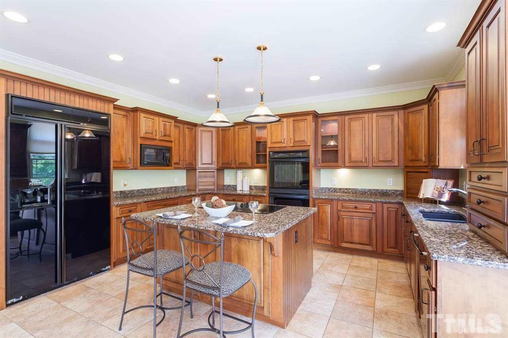 10500 Charmford Way Raleigh, NC 27615 - Photo 13 of 22 a kitchen with stainless steel appliances granite countertop wooden cabinets a stove a sink and a dining table