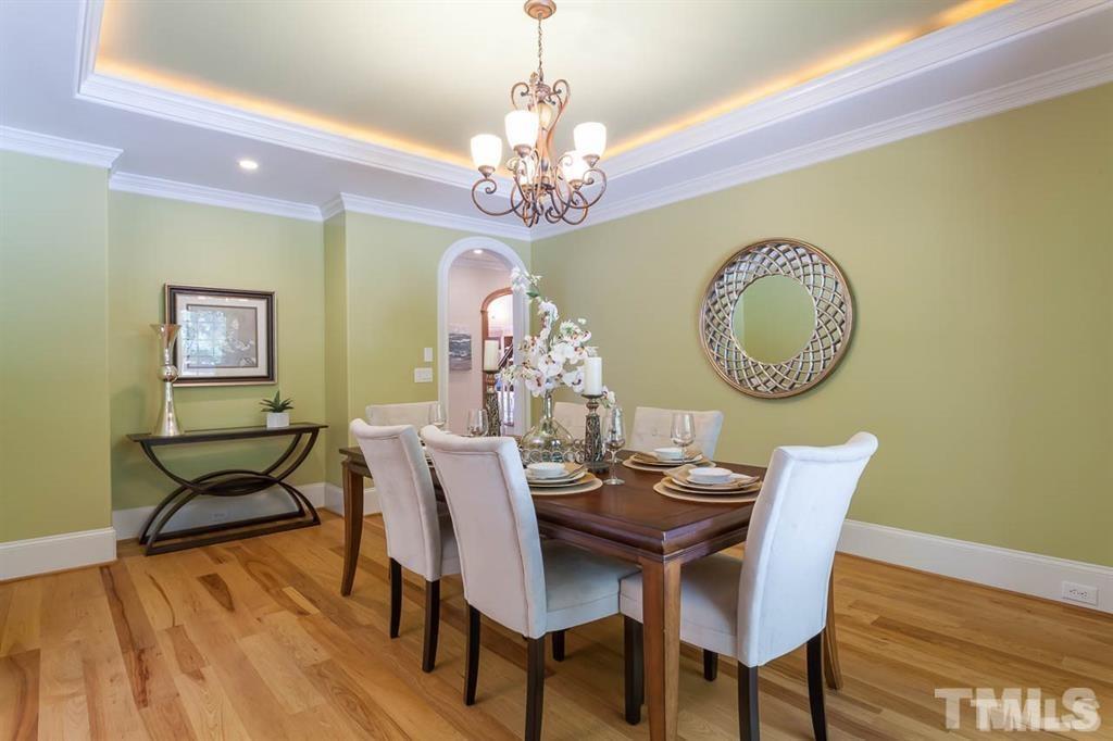 10500 Charmford Way Raleigh, NC 27615 - Photo 6 of 22 a dining room with wooden floor a chandelier a wooden table and chairs
