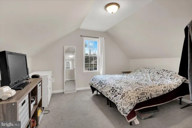 a bedroom with a bed and a flat tv screen on a dresser
