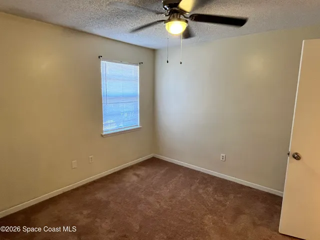 an empty room with a window and a fan