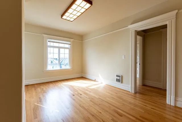 an empty room with wooden floor cabinet and windows