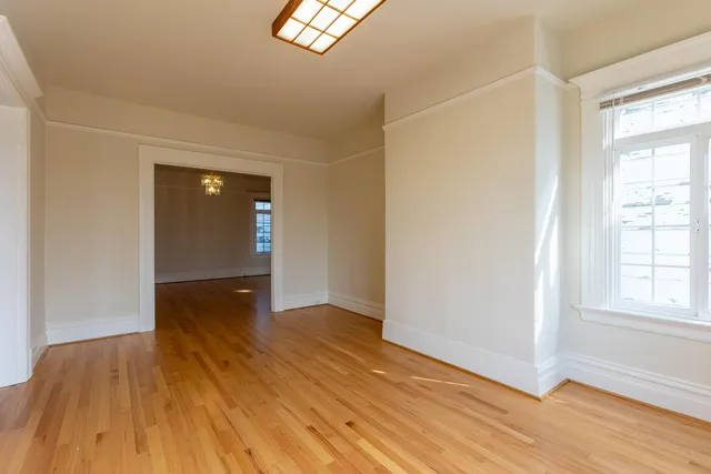 a view of an empty room with wooden floor and a window