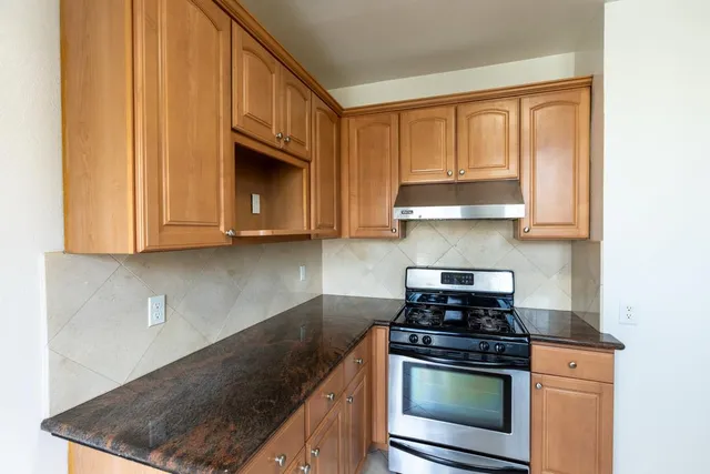 a kitchen with granite countertop wood cabinets and stainless steel appliances