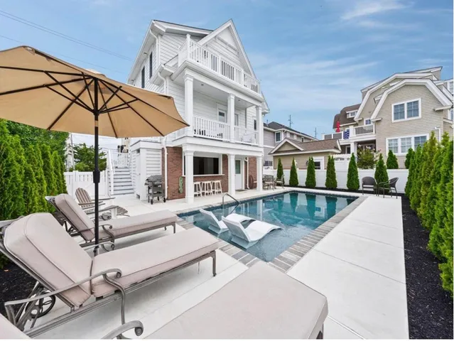 a view of a patio with couches table and chairs under an umbrella