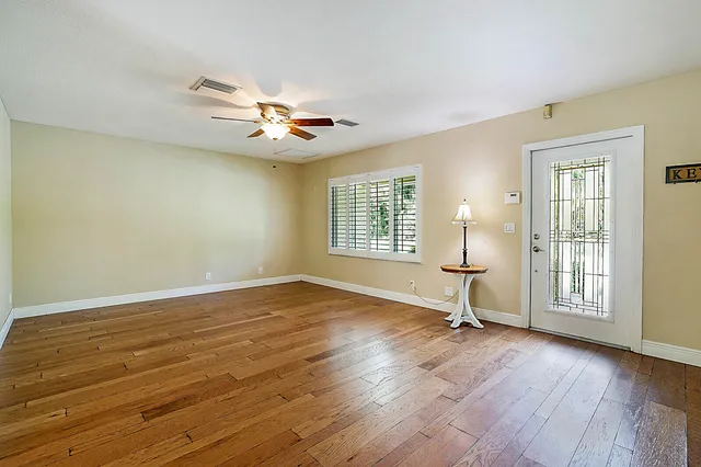 an empty room with wooden floor and windows