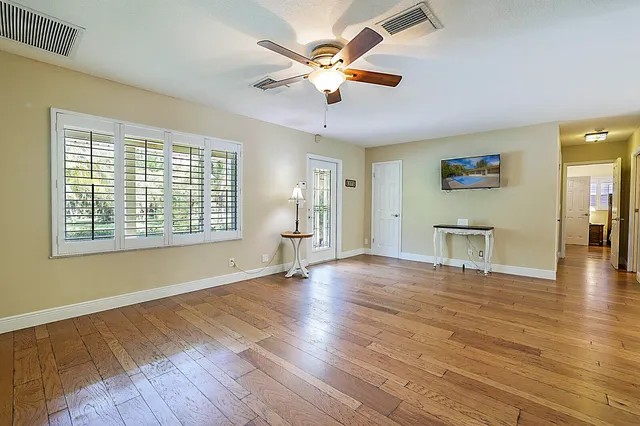 a view of an empty room with window and wooden floor