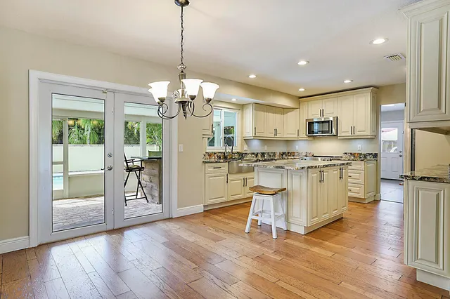 a view of kitchen with granite countertop a stove top oven a sink and a chandelier