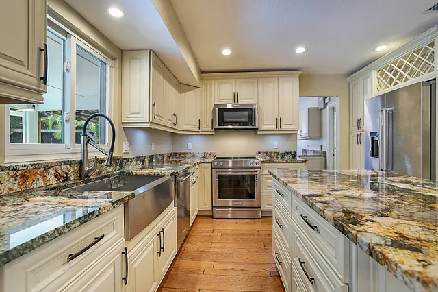 a kitchen with kitchen island granite countertop a sink appliances cabinets and a counter top space