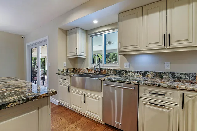 a kitchen with granite countertop white cabinets and stainless steel appliances