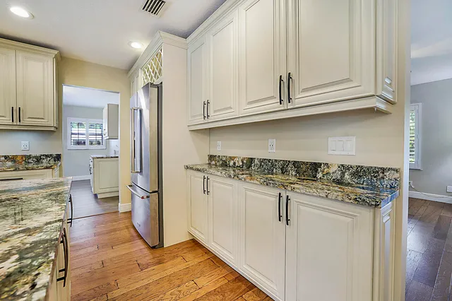 a kitchen with granite countertop a refrigerator sink and cabinets