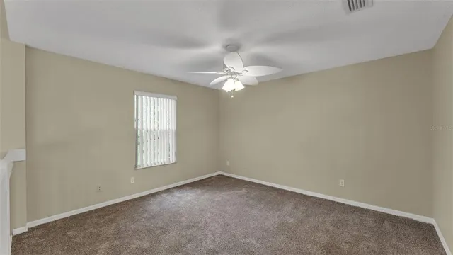 an empty room with windows and chandelier fan