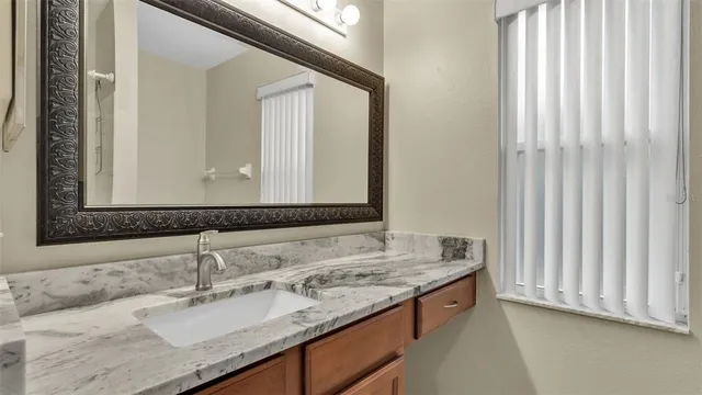 a bathroom with a granite countertop sink and a mirror