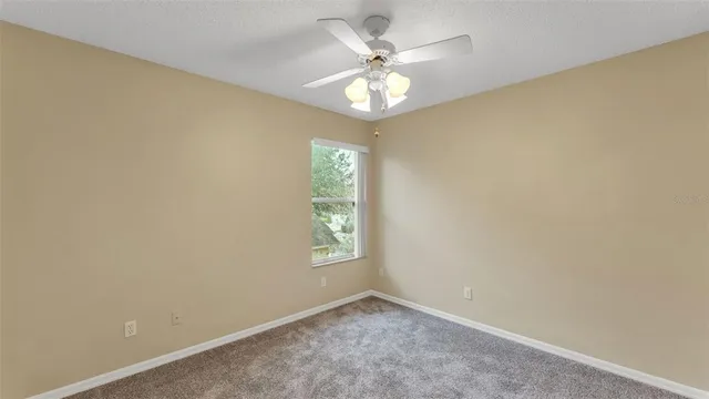 an empty room with windows and chandelier fan