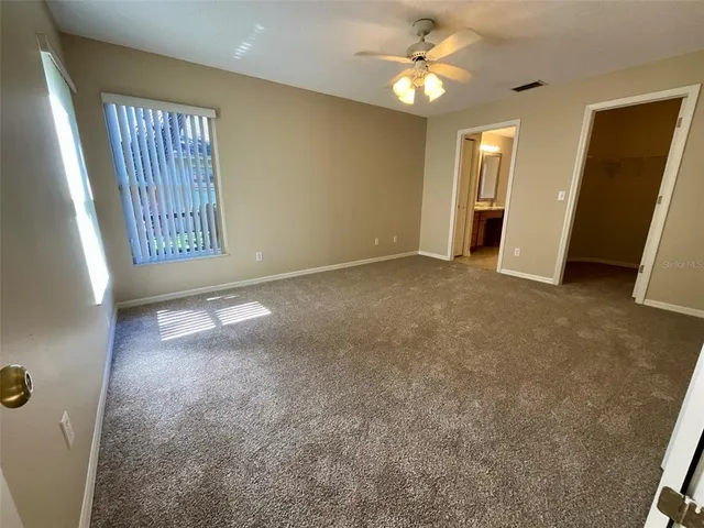 an empty room with windows and fan