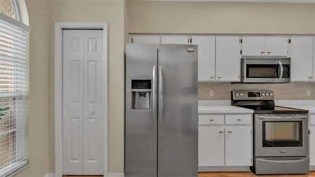 a kitchen with cabinets stainless steel appliances and a window