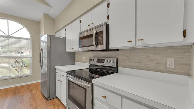a kitchen with stainless steel appliances white cabinets and a stove top oven