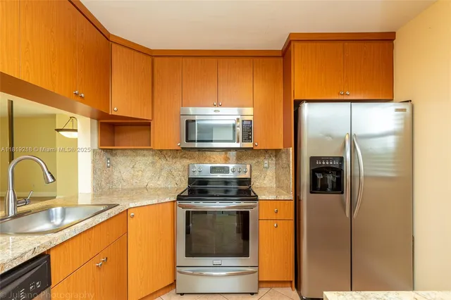 a kitchen with stainless steel appliances granite countertop a refrigerator a stove and a sink with wooden floor