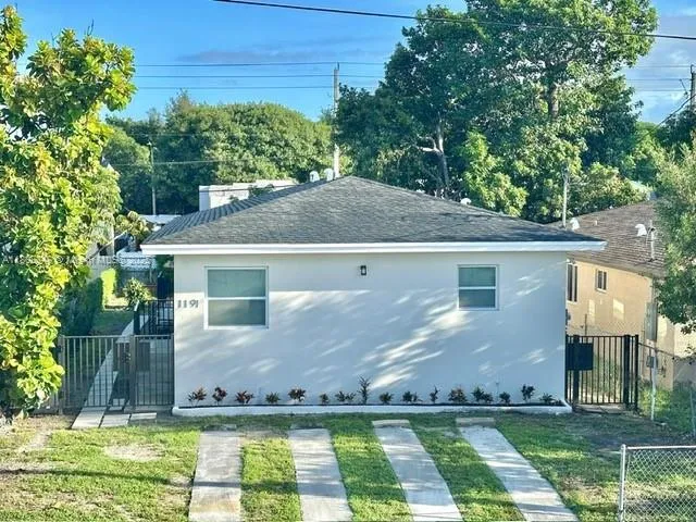 a view of a white house next to a yard with big trees
