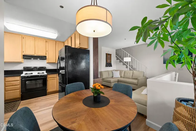 a kitchen with stainless steel appliances granite countertop a stove a refrigerator a sink a dining table and chairs with wooden floor