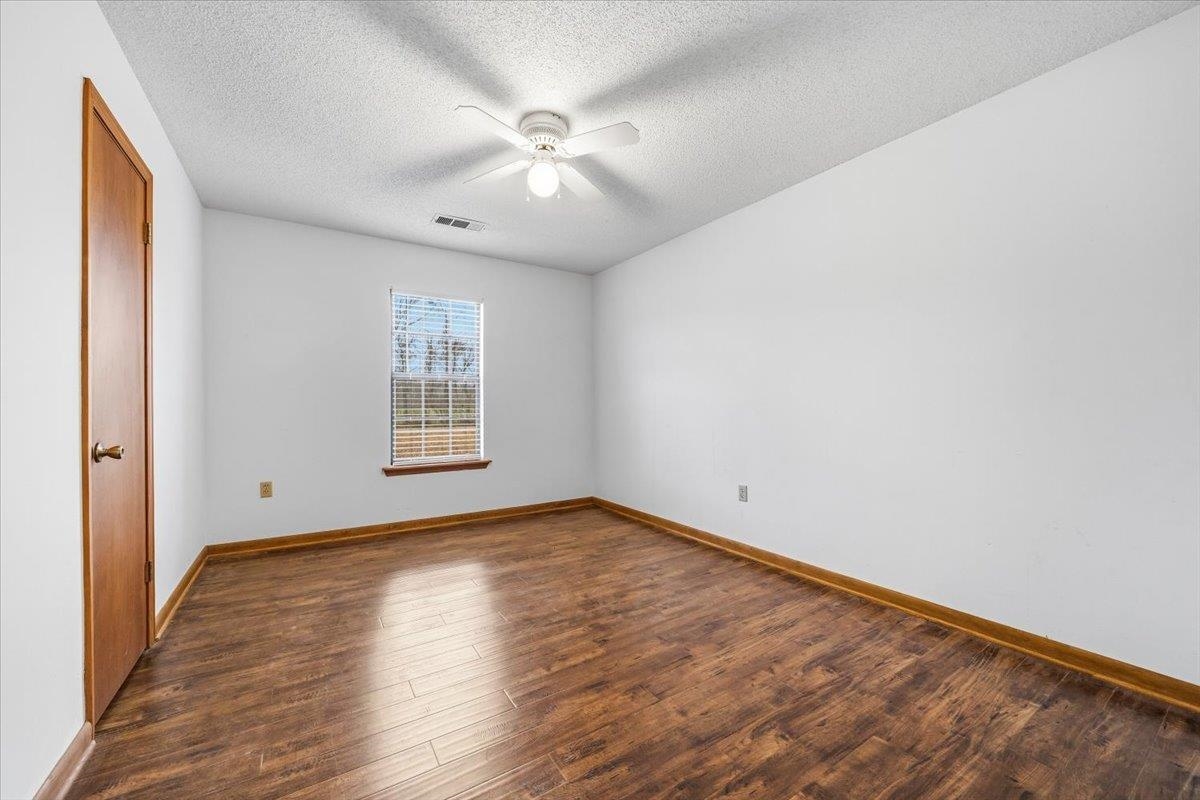 1426 Simmons Road Drummonds, TN 38023 - Photo 22 of 29 an empty room with wooden floor chandelier fan and windows