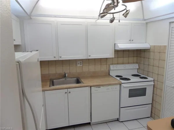 a kitchen with white cabinets and white appliances